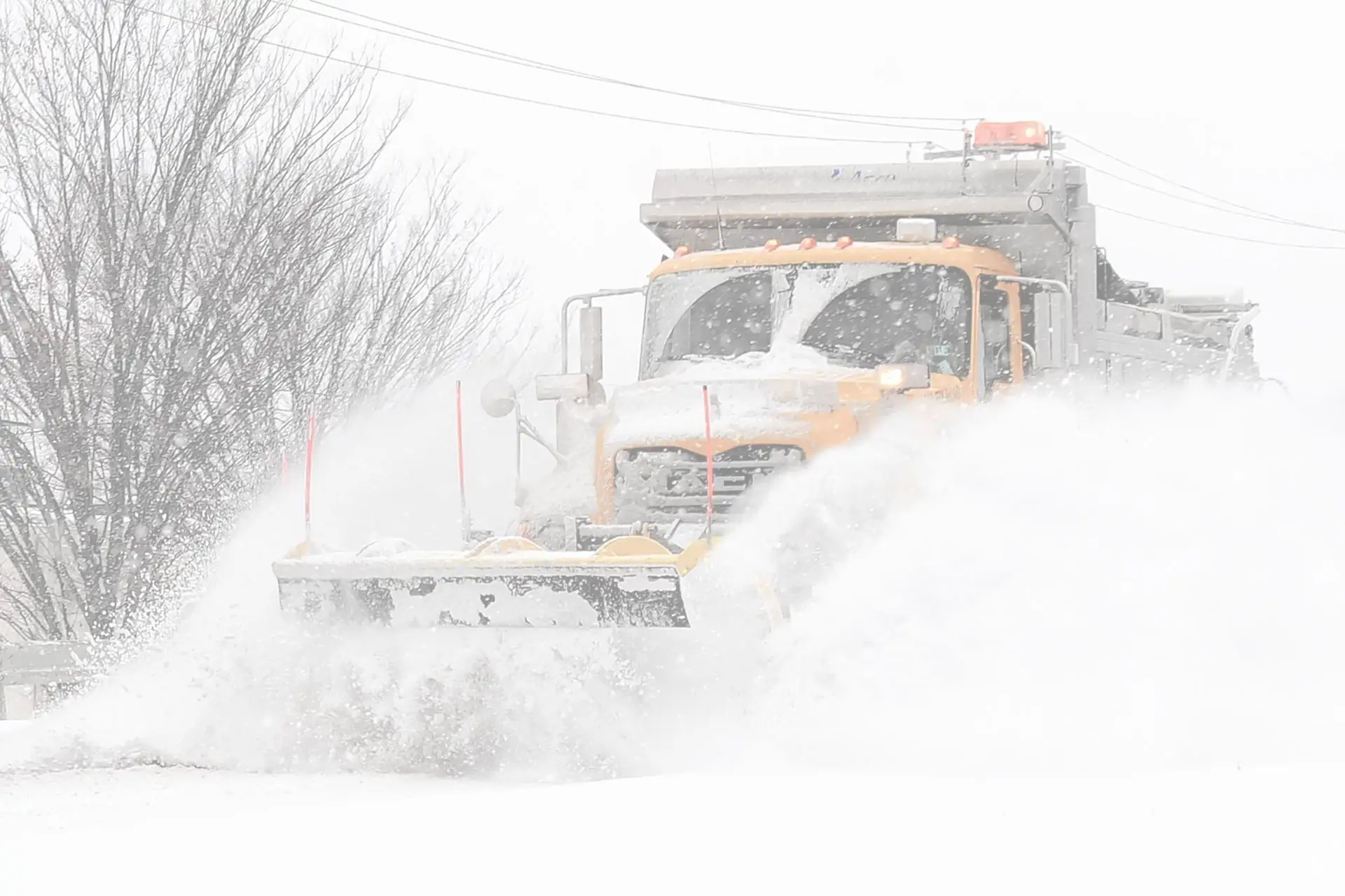 A plow truck clearing snow with the blade down